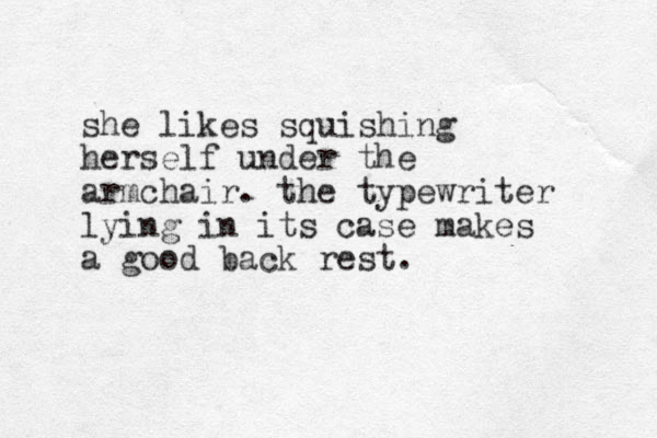 she likes squishing herself under the armchair. the typewriter lying in its case makes a good back rest.
